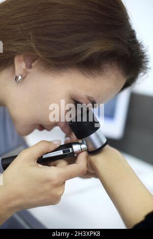 Closeup foto di dermatologo donna esamina nevo o segni di nascita sulla mano del paziente con dermatoscop Foto Stock