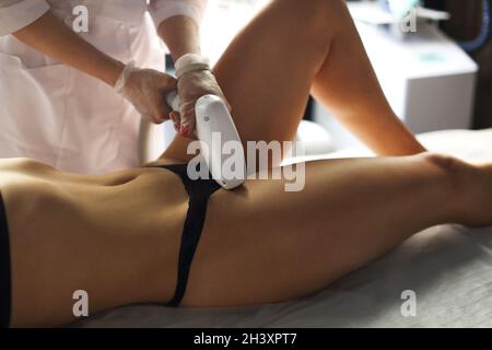 Medico in uniforme medica che fa la procedura di rimozione dei capelli del laser della zona bikini per la donna in clinica di bellezza Foto Stock