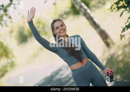 Stanco runner donna jogger bere acqua in bottiglia dopo il jogging nel parco all'aperto. Ascella umida e antitraspirante deodorante. Foto Stock