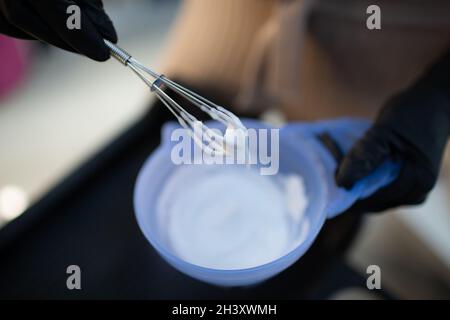 Giovane donna parrucchiere capelli morenti al salone di bellezza. Colorazione professionale delle radici dei capelli e miscelazione del colore della vernice Foto Stock