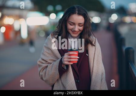 Giovane bella donna con tazza di caffè all'aperto. Foto Stock