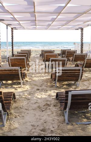 Splendida vista sul mare estivo e sulla spiaggia di sabbia con comodi lettini vuoti sotto l'ombra Foto Stock