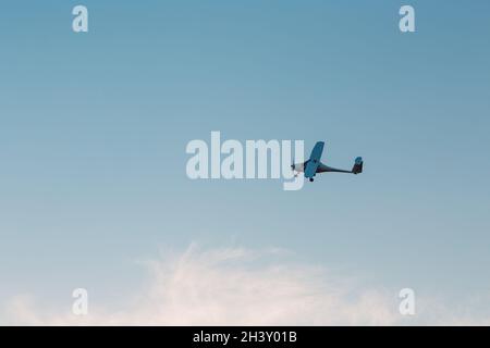 Piccolo aeroplano a motore singolo che vola contro il cielo del tramonto Foto Stock