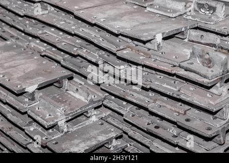 Parti in ferro del pezzo da lavorare per la posa di strutture metalliche di binari ferroviari in un cumulo in un impianto industriale. Foto Stock