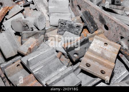 Parti in ferro del pezzo da lavorare per la posa di strutture metalliche di binari ferroviari in un cumulo in un impianto industriale. Foto Stock