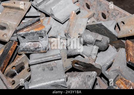 Parti in ferro del pezzo da lavorare per la posa di strutture metalliche di binari ferroviari in un cumulo in un impianto industriale. Foto Stock