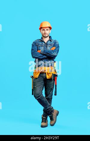 Ritratto a tutta lunghezza di sicuro bel lavoratore di costruzione maschile con braccia incrociate Foto Stock