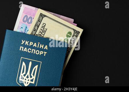 Passaporto cittadino ucraino con banconote in dollari USA e in hryvnia ucraine all'interno. Andando all'estero, concetto di tasso di cambio Foto Stock