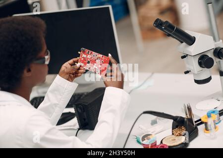 Scienziata afroamericana che lavora in laboratorio con strumenti elettronici Foto Stock