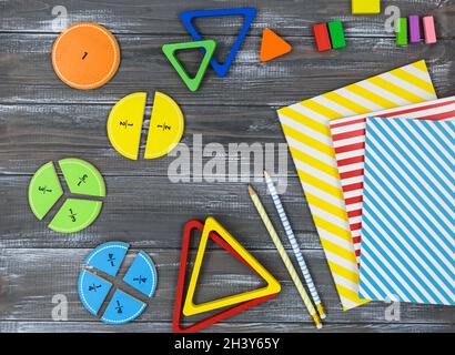 Frazioni multicolore, blocchi, taccuino su un tavolo di legno grigio. Ritorno a scuola, matematica divertente, giochi per l'asilo, istruzione prescolare. Foto Stock