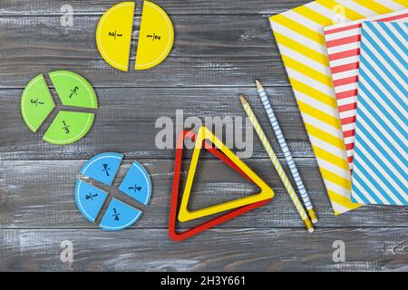 Frazioni multicolore, blocchi, taccuino su un tavolo di legno grigio. Ritorno a scuola, matematica divertente, giochi per l'asilo, istruzione prescolare. Foto Stock