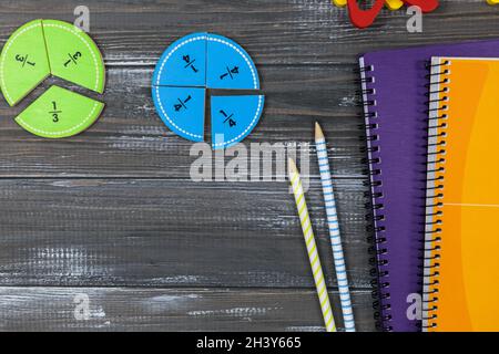 Frazioni multicolore, blocchi, taccuino su un tavolo di legno grigio. Ritorno a scuola, matematica divertente, giochi per l'asilo, istruzione prescolare. Foto Stock