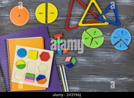 Frazioni multicolore, blocchi, taccuino su un tavolo di legno grigio. Ritorno a scuola, matematica divertente, giochi per l'asilo, istruzione prescolare. Foto Stock