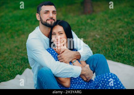 Giovane donna adulta e uomo che abbracciano coppia pic-nic a prato verde erba nel parco. Foto Stock