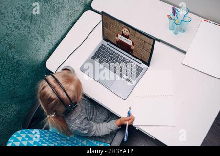 Giovane studentessa bambina con tachigrafo tiene un poster bianco in apprendimento pratico dello schermo del portatile e preparazione del ritorno a scuola Foto Stock