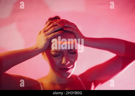 La giovane donna adulta tiene le mani sulla testa e soffre Espressioni facciali con mal di testa di parole sul viso Foto Stock