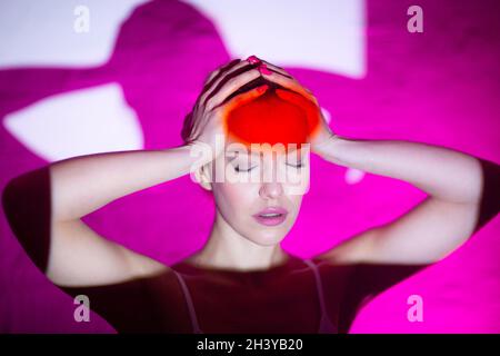 Giovane donna con mal di testa e fronte di colore rosso Foto Stock