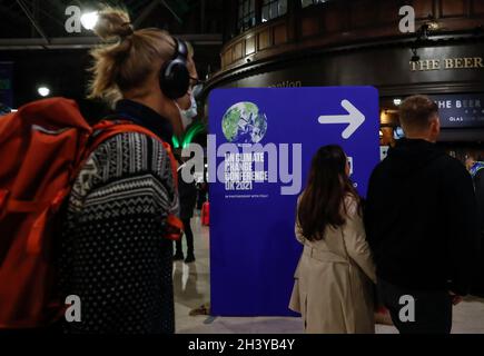 Glasgow, Regno Unito. 30 Ott 2021. La gente passa da un cartello presso la stazione ferroviaria centrale di Glasgow, Scozia, Regno Unito il 30 ottobre 2021. La 26a Conferenza delle parti sul cambiamento climatico delle Nazioni Unite (COP26) è prevista a Glasgow, Scozia, dal 31 ottobre al 12 novembre. Questo è il primo di questo tipo dall'entrata in vigore dell'accordo di Parigi. Credit: Han Yan/Xinhua/Alamy Live News Foto Stock