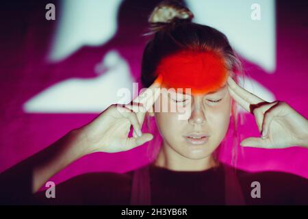 Giovane donna con mal di testa e fronte di colore rosso Foto Stock