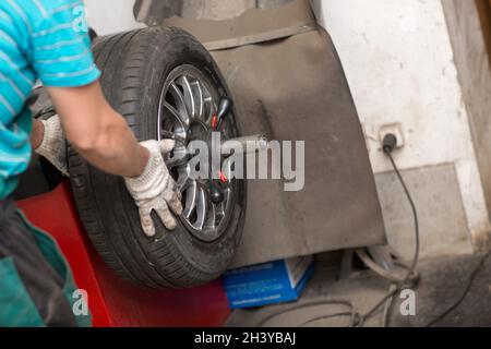 Equilibratura delle ruote. Macchina equilibratrice per auto in riparazione. Foto Stock