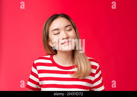 Primo piano romantico tenero felice asiatico donna inclinazione testa vicino occhi gioiosamente sorridente ricordando bel momento bello, daydreaming delic Foto Stock