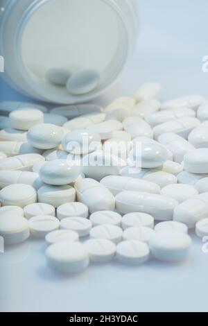 Helsinki / Finlandia - 31 OTTOBRE 2021: Primo piano di pillole bianche su sfondo bianco. Contenitore bianco per pillole sullo sfondo. Foto Stock