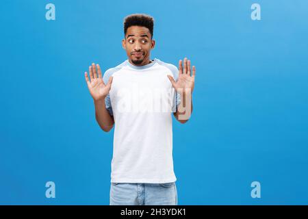 L'uomo che dice alla polizia non era lui. Unimpliced senza indizio intenso africano americano maschio con barba in casual vestito che alza palme i Foto Stock