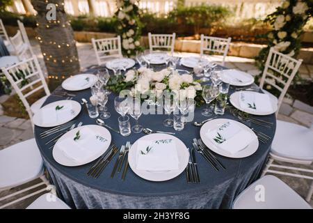Matrimonio. Banchetto. Le sedie e il tavolo rotondo per gli ospiti, serviti con  posate, piccolo ulivo e coperti da una tovaglia bianca Foto stock - Alamy