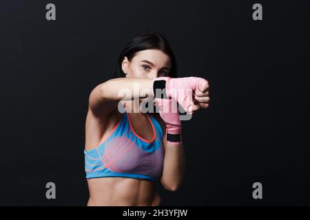 Sportivo muay thai donna boxer in posa in studio di formazione su sfondo nero. Foto Stock