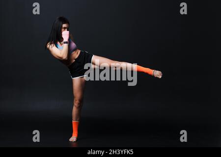 Sportivo muay thai donna boxer in posa in studio di formazione su sfondo nero. Foto Stock