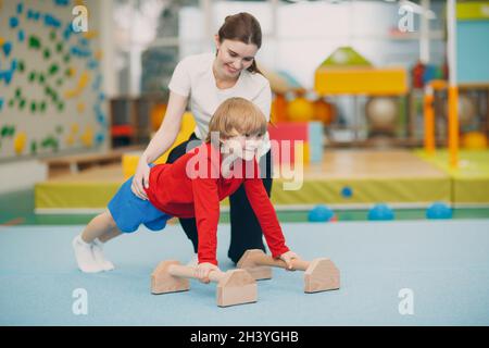 I bambini che fanno le esercitazioni spingono in su nella palestra all'asilo o alla scuola elementare. Concetto di sport e fitness per bambini. Foto Stock