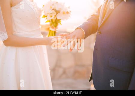 Lo sposo mette l'anello sul dito dello sposo durante la cerimonia nuziale Foto Stock