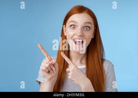 Carismatico impressionato sorpreso buon-osservante felice sorridente ragazza rossa cute dire wow che grinning stupito occhi larghi che puntano uppe Foto Stock