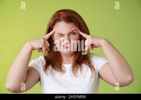 Decisione difficile. Perplessi esitante rosso testa di mezza età 50s donna cercando risolvere puzzle sguardo sconcertato sbirciato occhi vicini Foto Stock