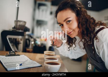 Tazza degustazione ragazza degustazione Degostation caffè prova di qualità. Tazza di caffè Foto Stock