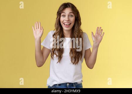 Allegro felice uscita carino positivo giovane ragazza sorridente ampiamente alzare entrambi i palmi agitando le mani ciao saluto gesto benvenuto ven Foto Stock