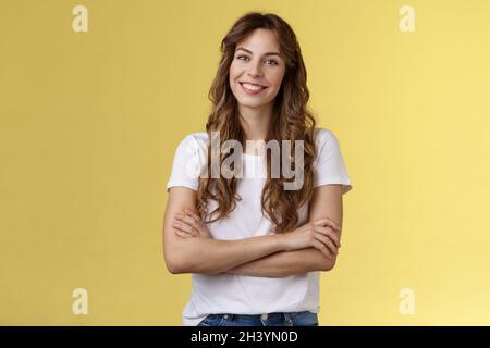 Sicuro spensierato vivace sorridente donna freelancer professionale cross braccia petto auto-sicuro posa stand confortevole bianco t-sh Foto Stock