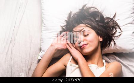 Giovane ragazza carina con un'espressione divertente si trova sul cuscino nella sua stanza accogliente. Foto Stock