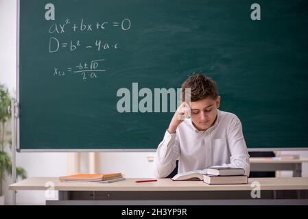 Scolaro che studia matematica di fronte alla lavagna Foto Stock