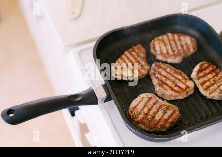 Quattro bistecche tostate su una padella alla griglia, con rosmarino tritato finemente. Foto Stock