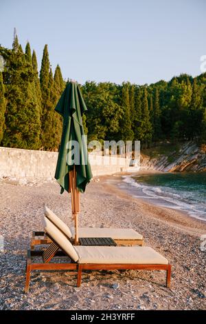 Primo piano su una spiaggia di sabbia con lettini in legno. La spiaggia reale vicino a Villa Milocer, montenegro. Foto Stock