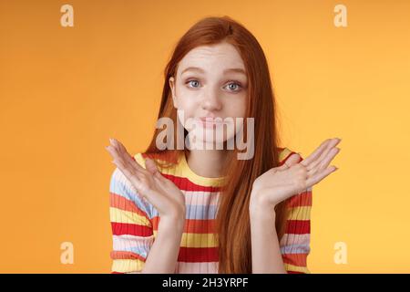 Senza indizio giovane redhead stupido europeo ragazza 20s shrugging mani sparse di lato che puzzano scusa non può rispondere in piedi Foto Stock