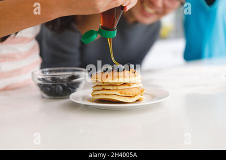 Il padre asiatico guarda la figlia che prepara la prima colazione frittelle in cucina Foto Stock