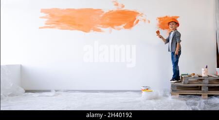 riparazione di una nuova casa. Bambino ragazzo dipinse il muro con vernice nell'appartamento. I bambini sono progettisti domestici. Concetto di ristrutturazione della casa. Banner. Foto Stock