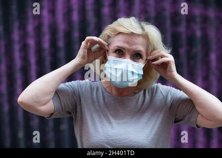 Donna anziana in maschera ritratto esterno. Vecchia donna invecchiata indossare maschera medica protettiva. Foto Stock