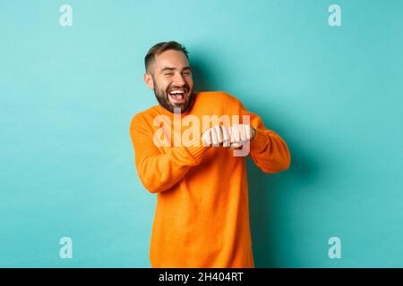 L'uomo felice danzando e celebrando il successo, sentendosi come vincitore, sorridendo e gioendo, sfondo azzurro chiaro Foto Stock