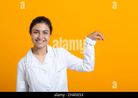 Ritratto di medico indiano donna in abito medico bianco che tiene dita modello vaccino covid-19 o altro materiale medico isolato Foto Stock