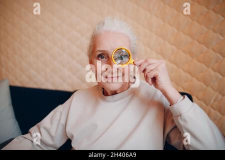 La donna anziana con lente di ingrandimento in mano Foto Stock