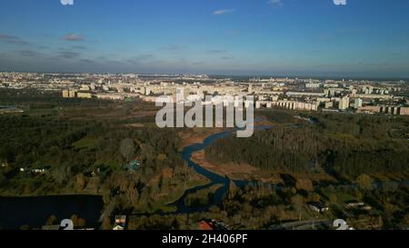 Parco autunnale della città con un fiume. Volare nei sobborghi. All'orizzonte si trovano alti edifici. Fotografia aerea. Foto Stock