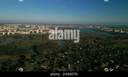 Parco autunnale della città con un fiume. Volare nei sobborghi. All'orizzonte si trovano alti edifici. Fotografia aerea. Foto Stock